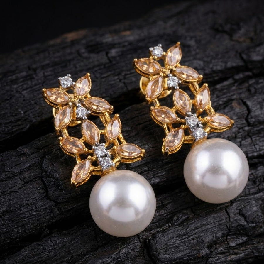 Pink stone and pearl drop earrings lying on black textured wood
