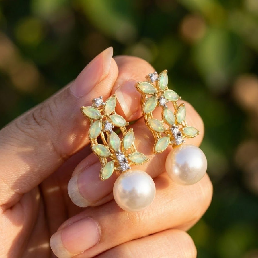Elegant pearl drop earrings with deep green marquise stones displayed on white background