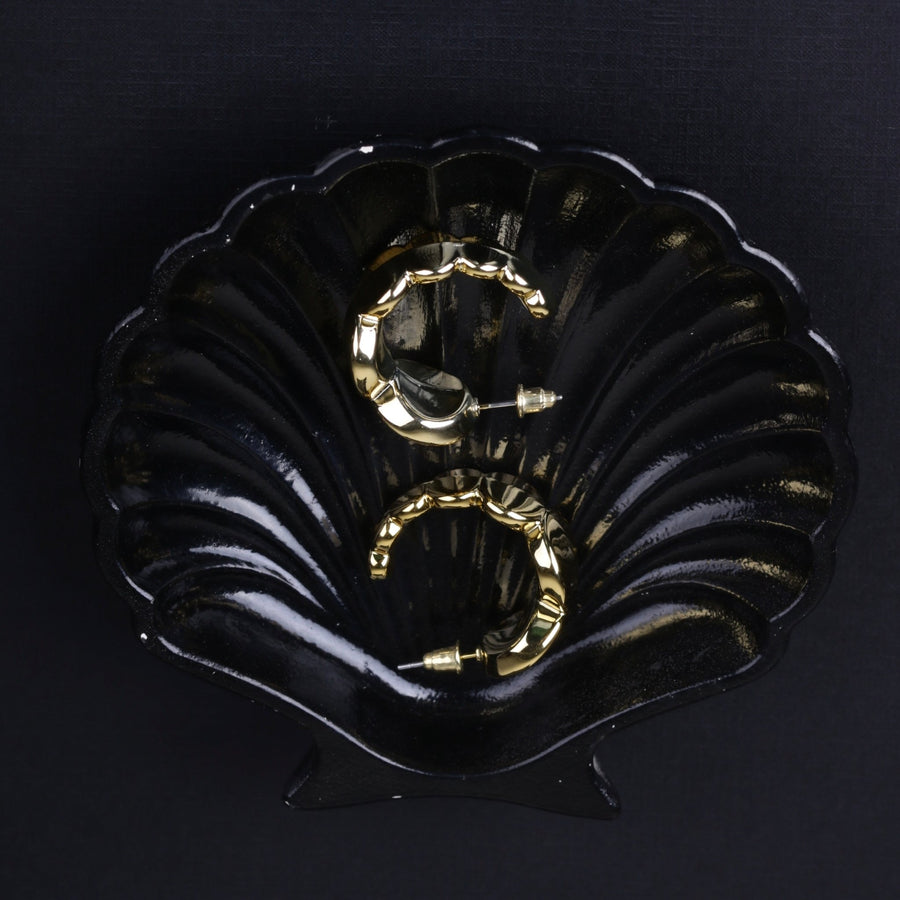 Gold chunky hoop earrings placed inside black decorative shell-shaped dish showing the post-back closure