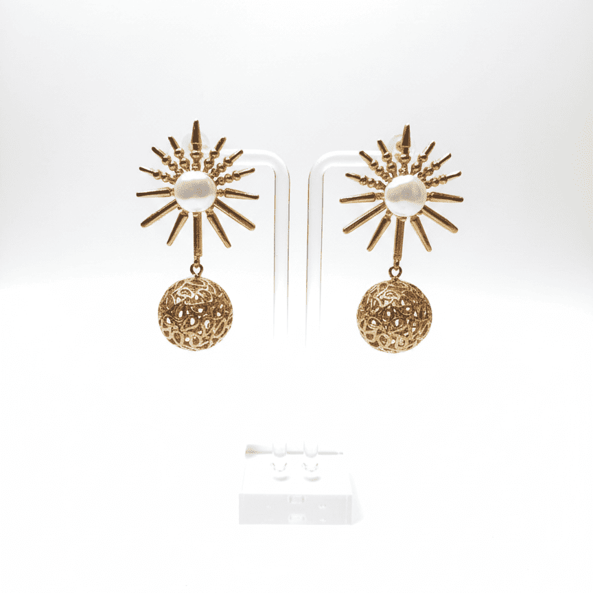 Gold sunburst pearl earrings with intricate filigree spheres shown on white background with bright lighting