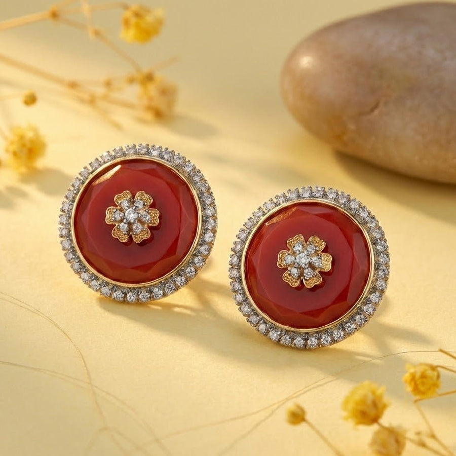 Model wearing red round stud earrings with a sparkling halo and flower motif, dressed in deep red embroidered attire