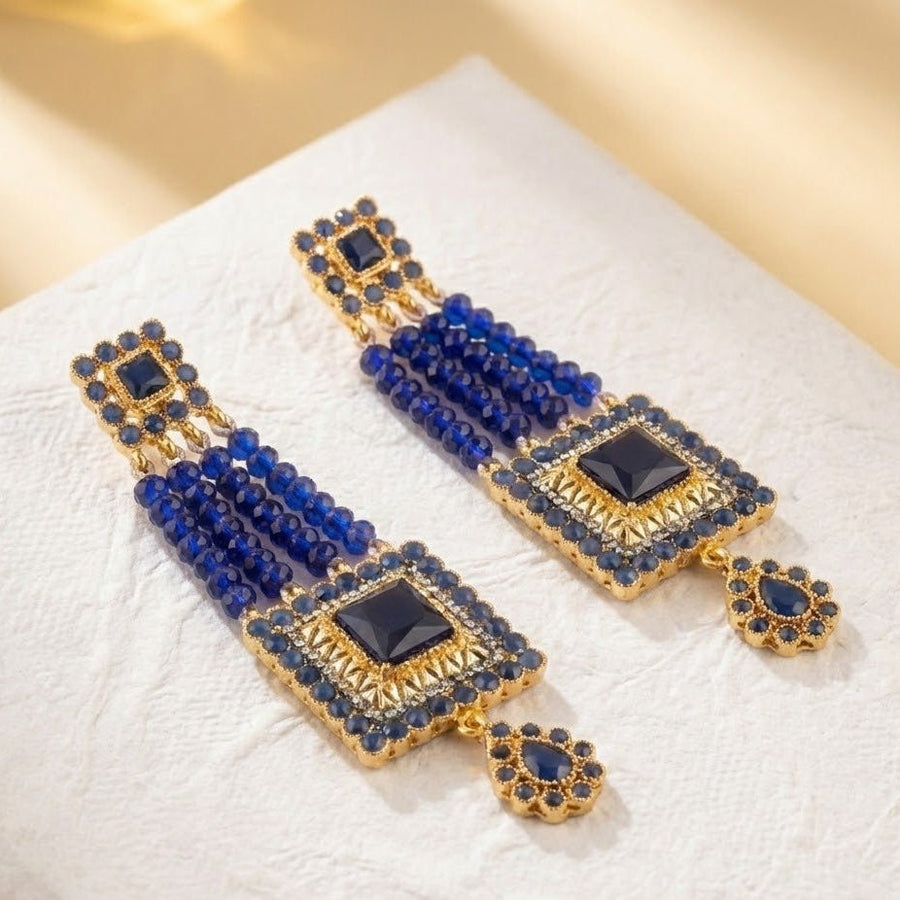 Blue gemstone bead earrings held side by side in both hands showcasing size and color