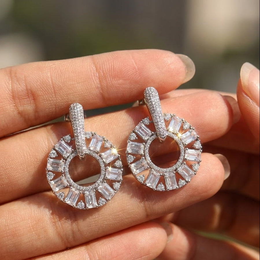 Silver plated clear stone circle drop earrings held in hand showcasing sparkle