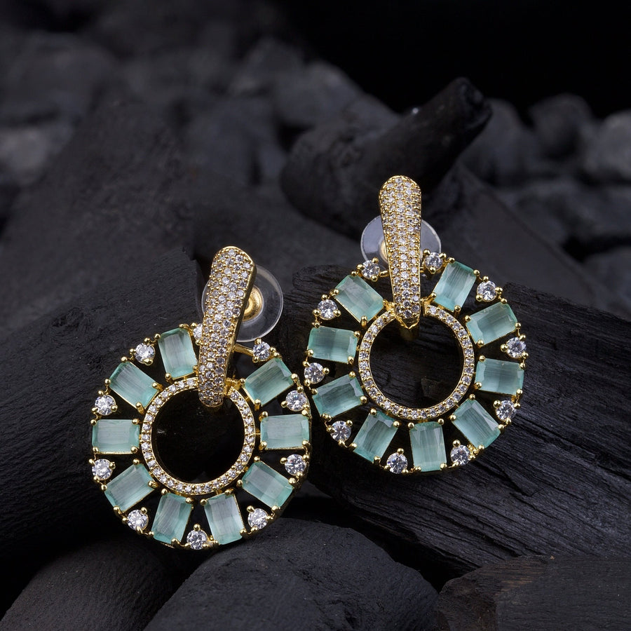 Pair of gold plated mint green baguette-cut stone earrings with clear crystals on black background