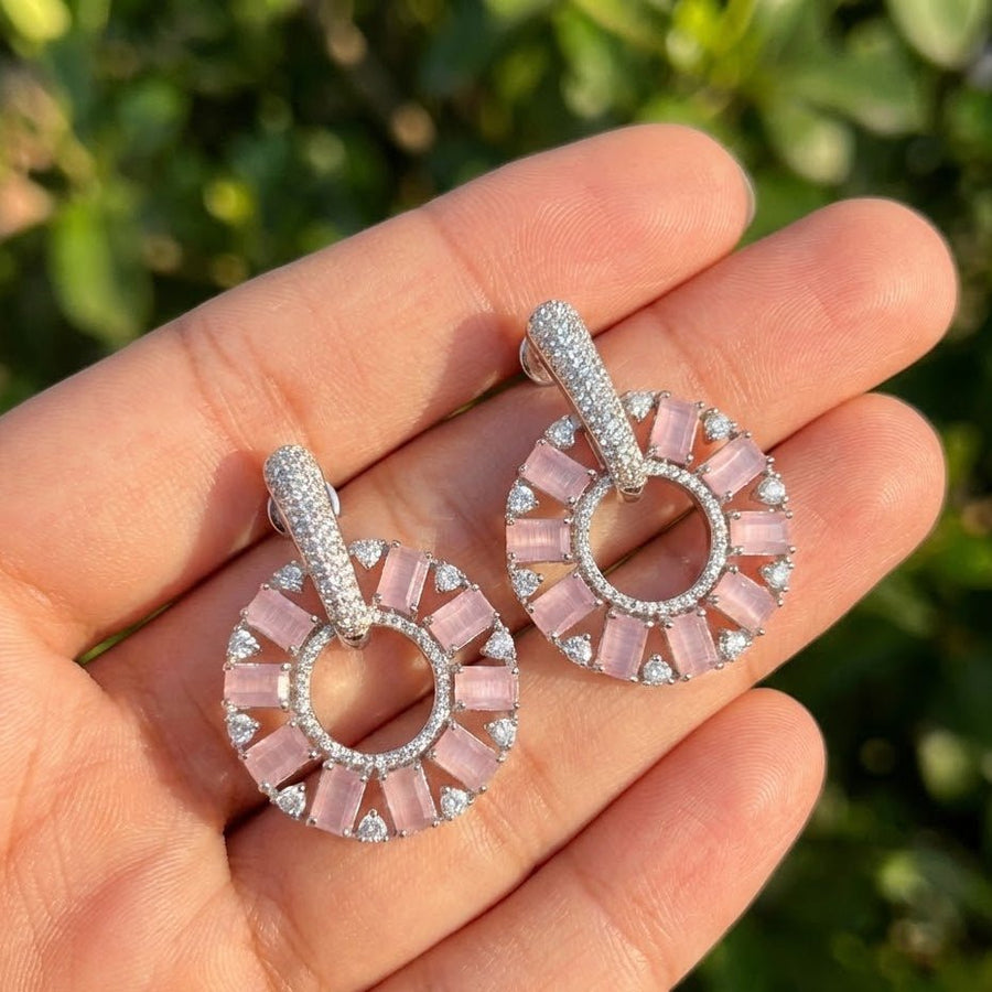Close-up image of gold plated pink stone circle drop earrings on plain white background