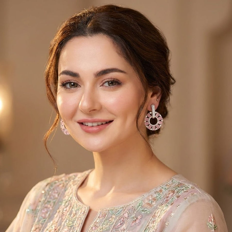 Detailed view of gold plated pink baguette cut stone circle drop earrings displayed on black