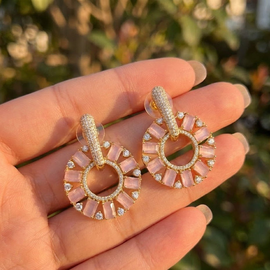 Pink stone circle drop earrings held in hand under natural sunlight