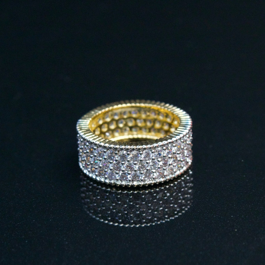 Two-tone gold and silver cubic zirconia band ring showing detailed milgrain edge on black reflective surface