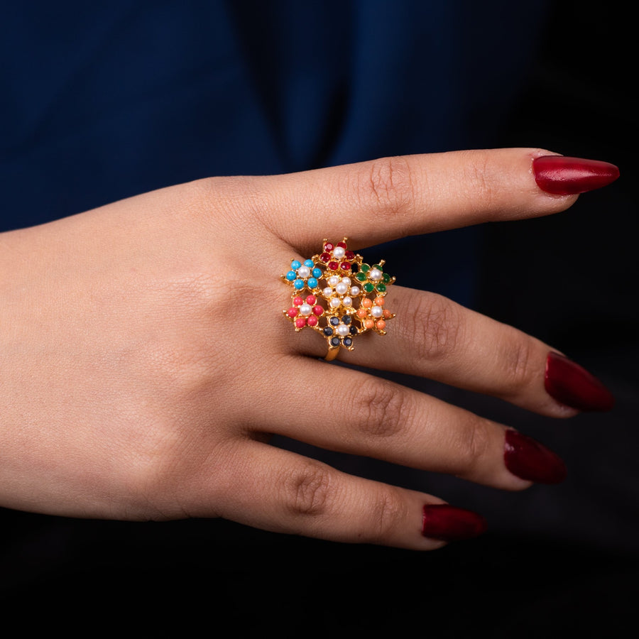 Top perspective of a woman’s hand adorned with the multicolor floral zircon ring, showcasing the vibrant stones and pearl-centered flower motifs against a dark blue backdrop