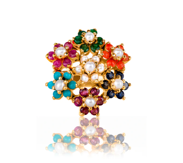Studio shot of a multicolor floral zircon ring with gold plating displaying vibrant flower motifs highlighted by small pearls and zircon stones, shown with reflection beneath