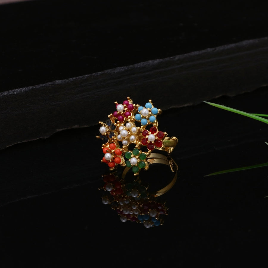 Side view of the multicolor floral zircon ring placed on a black reflective surface, showing intricate gold and colorful stones composing floral designs