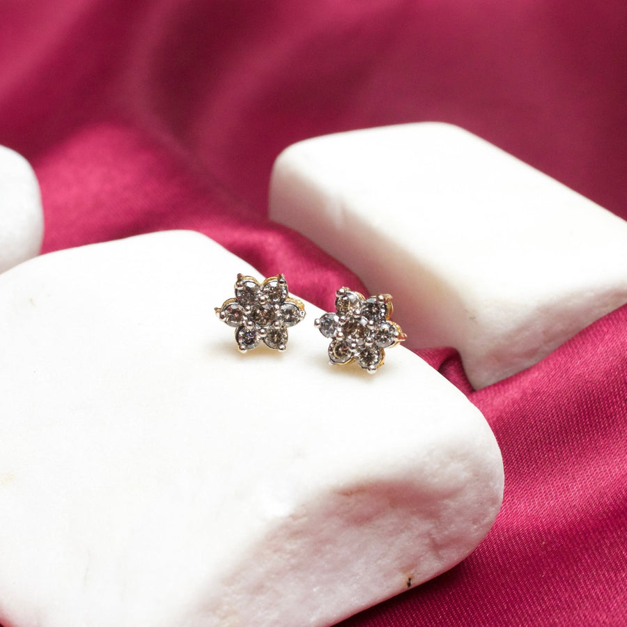 Floral stud earrings with clear sparkling gemstones on white stone display against a magenta fabric background