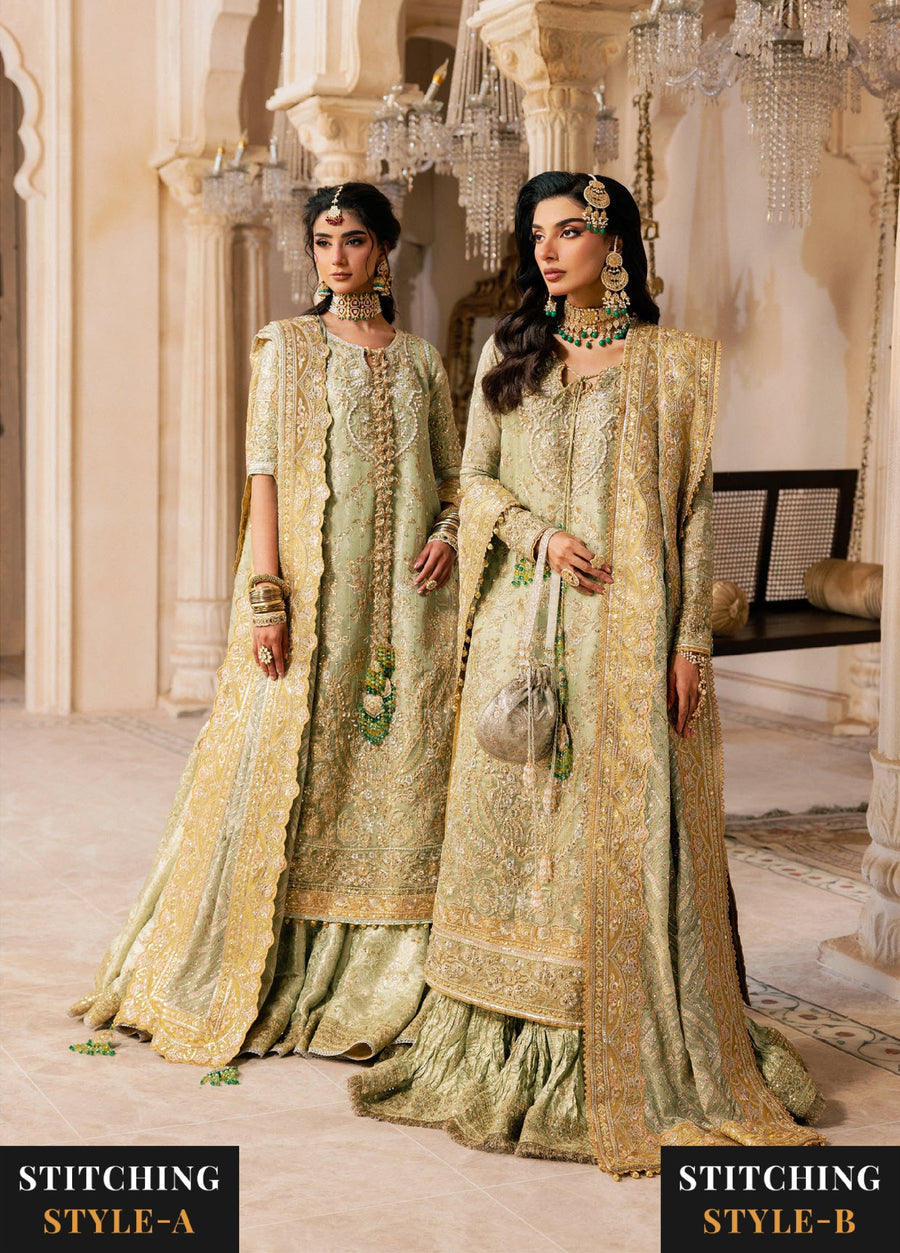Two women wearing matching sage green embroidered formal suits with gold zari accents, styled in two different stitching styles standing in an ornate venue.