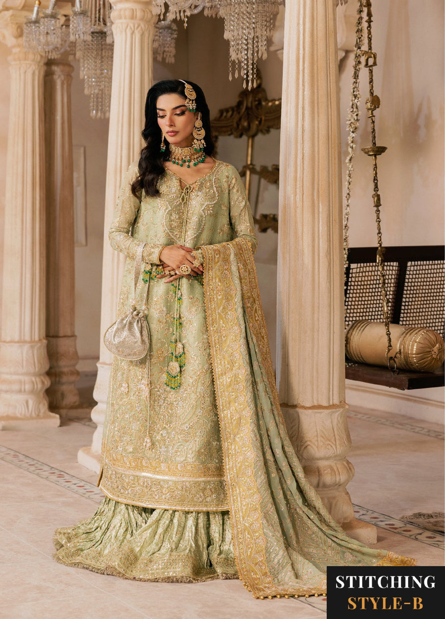Woman in sage green embroidered formal suit holding a silver pouch, styled in the alternative stitching style with intricate bead and zari embroidery.