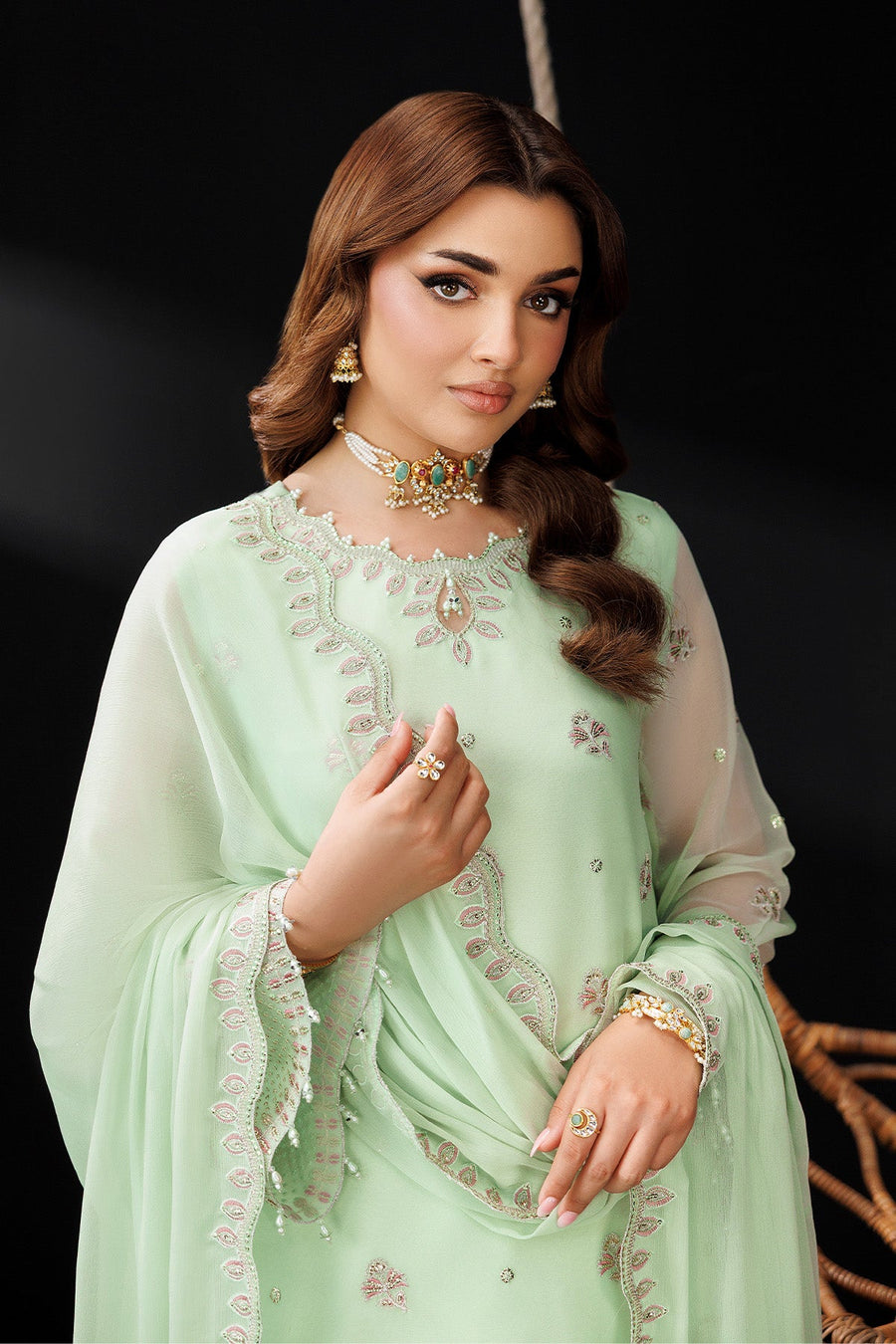 Model holding embroidered chiffon dupatta draped gracefully in pastel green three-piece suit