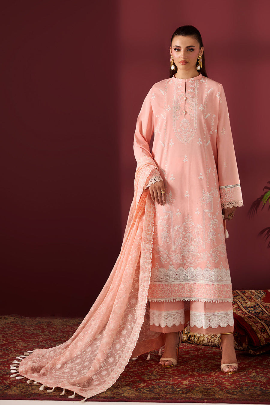 Woman modeling embroidered peach lawn suit with white floral embroidery and tassel dupatta
