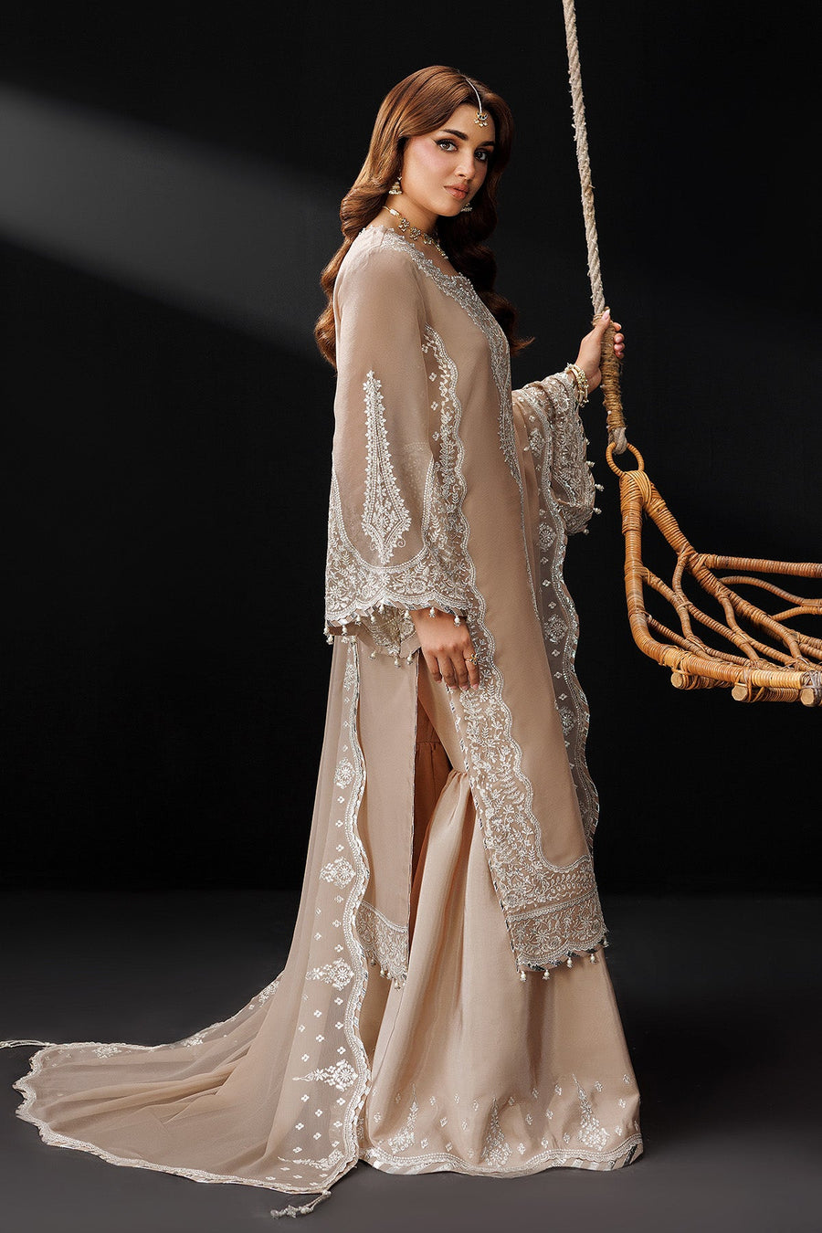 Model standing posing in beige embroidered kameez set highlighting fine threadwork and soft fabric texture