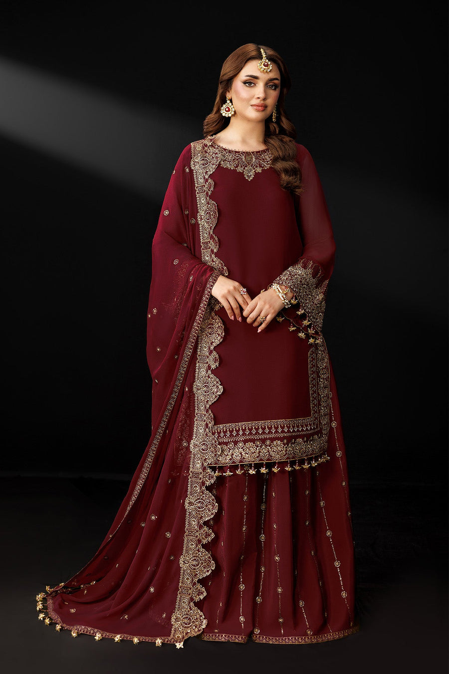 Portrait of woman in maroon embroidered suit with coordinated gold jewelry