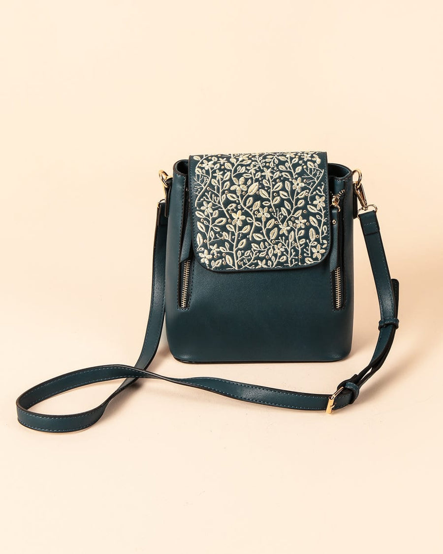 Deep teal sling bag with intricate cream floral embroidery on the cover flap, featuring an adjustable strap and gold-tone hardware.