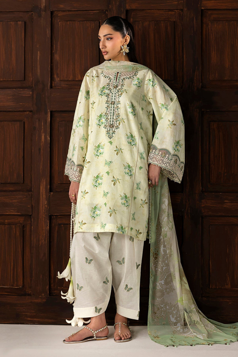 Full length view of model standing wearing embroidered lawn suit with butterfly print pants and green sheer dupatta