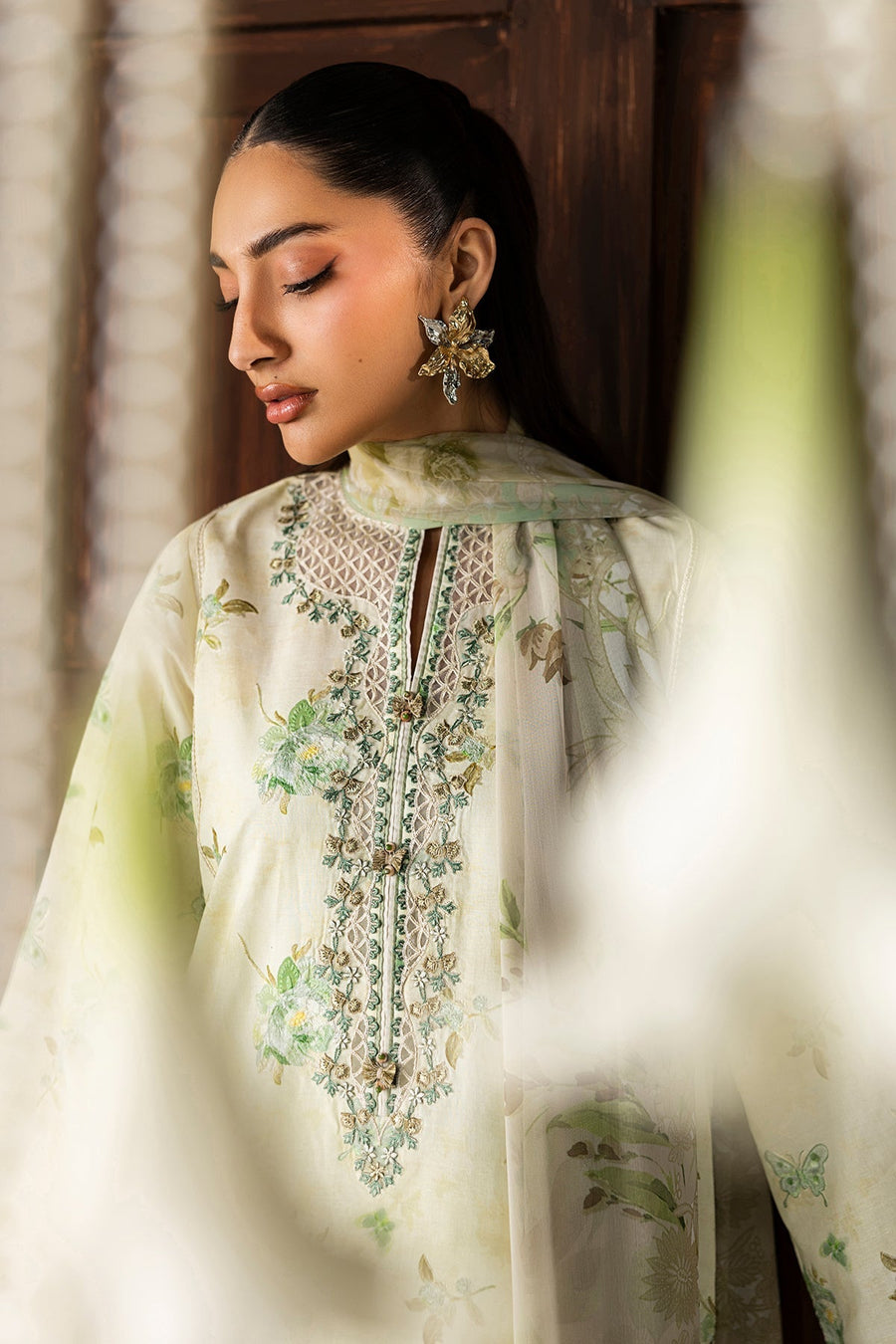 Model posing with pearl accessory holding embroidered lawn shirt side view