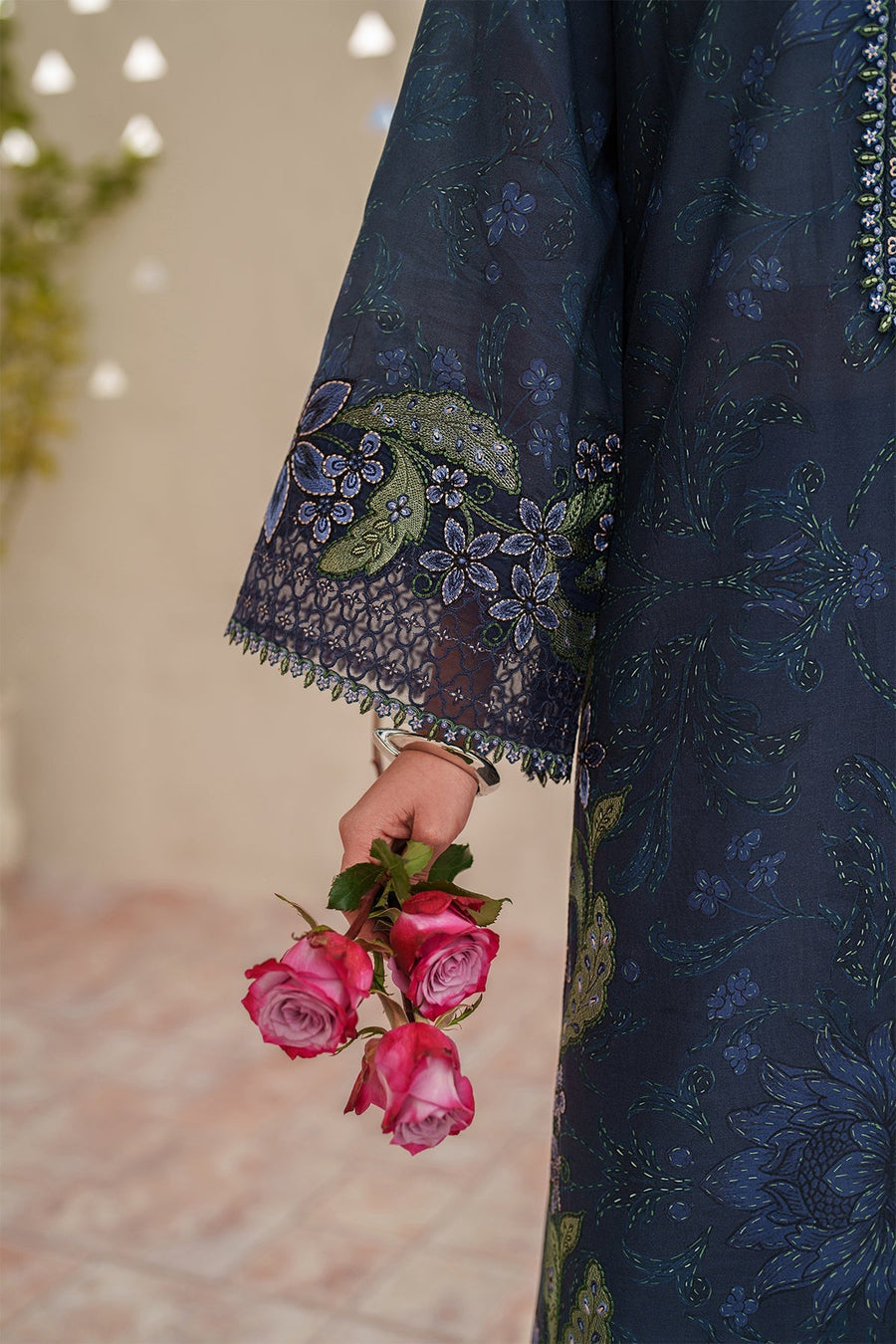 Close-up of delicate embroidered sleeves and navy trouser paired with silver strappy heels