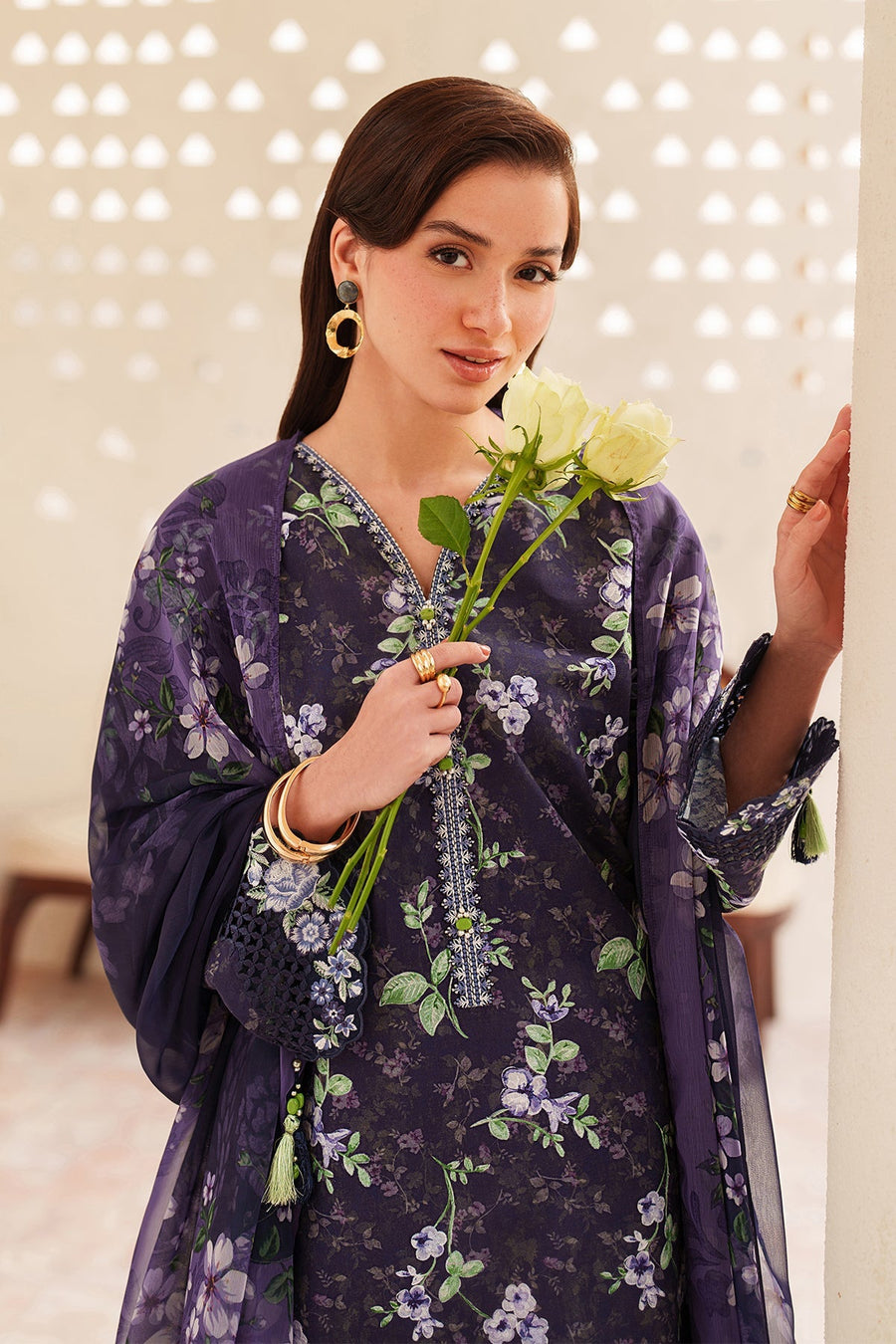 Detailed shot of a woman's face and upper body in a navy floral embroidered kurta, accessorized with statement gold earrings and soft makeup.