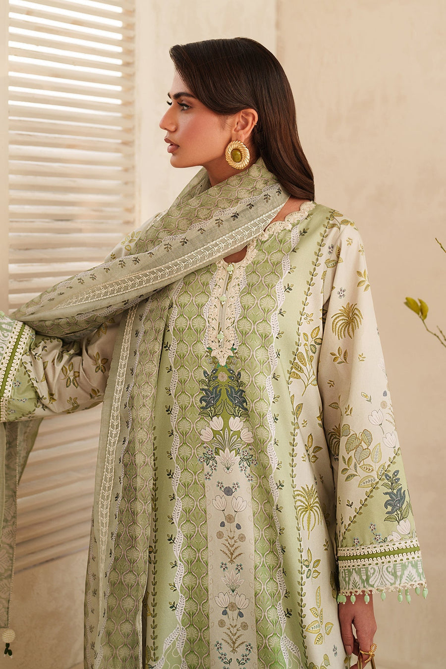 Close-up of embroidered neckline and sleeve with intricate floral and lace details in green and white tones