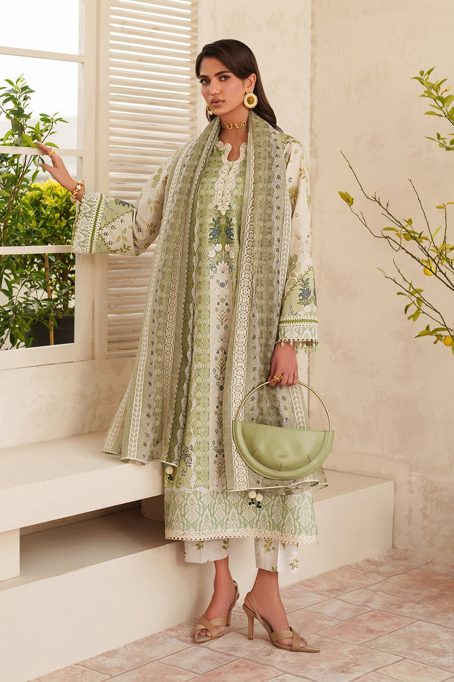 Front view of woman wearing elegant green and white embroidered lawn suit with matching dupatta and beige high-heel sandals, holding a light green handbag