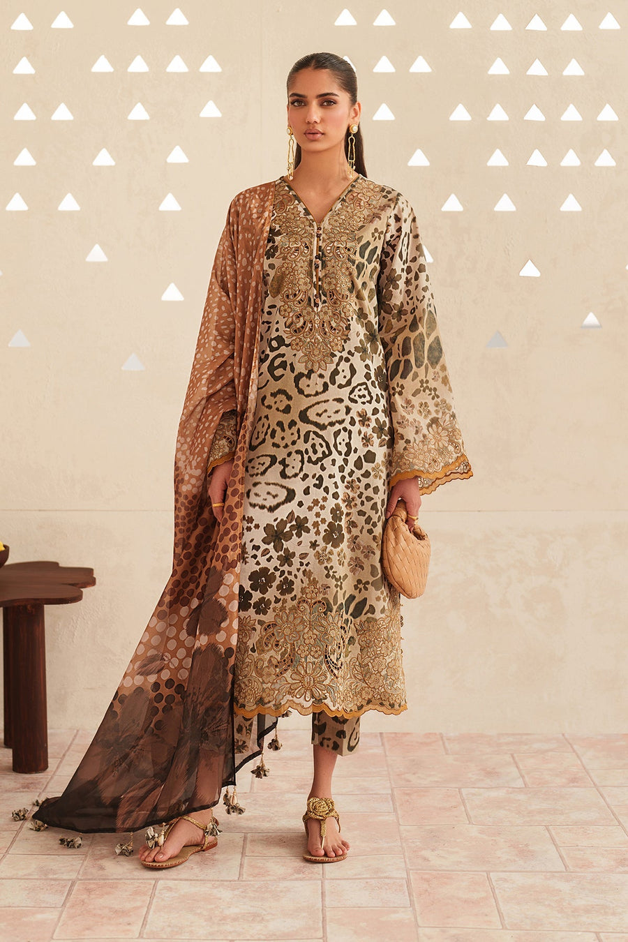 Front view of woman wearing embroidered lawn suit with animal and floral print, paired with matching dupatta and gold sandals