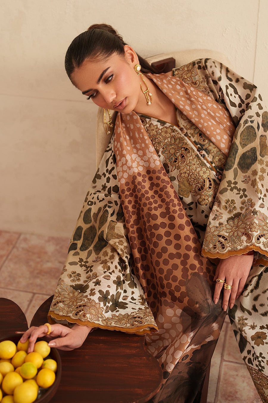 Model holding edge of embroidered sleeve showing fine floral organza embroidery and scalloped edges