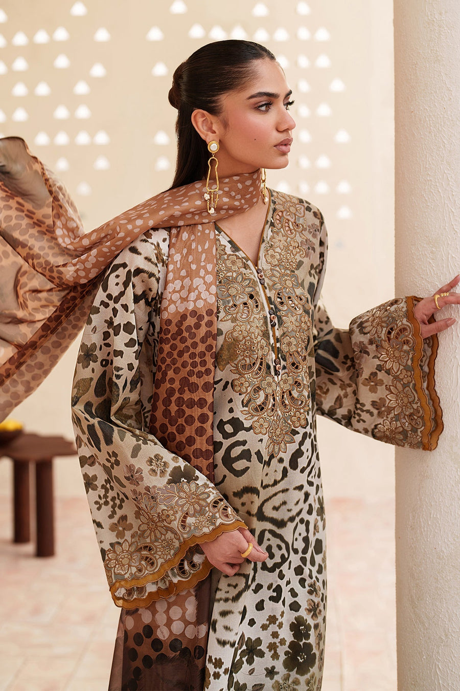 Model seated with embroidered lawn suit and draped dupatta showing elegant embroidery and fabric texture