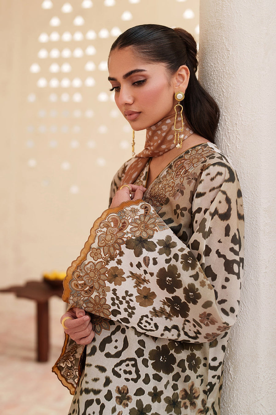 Close-up detail of embroidered hem and matching printed trousers with woven tan clutch