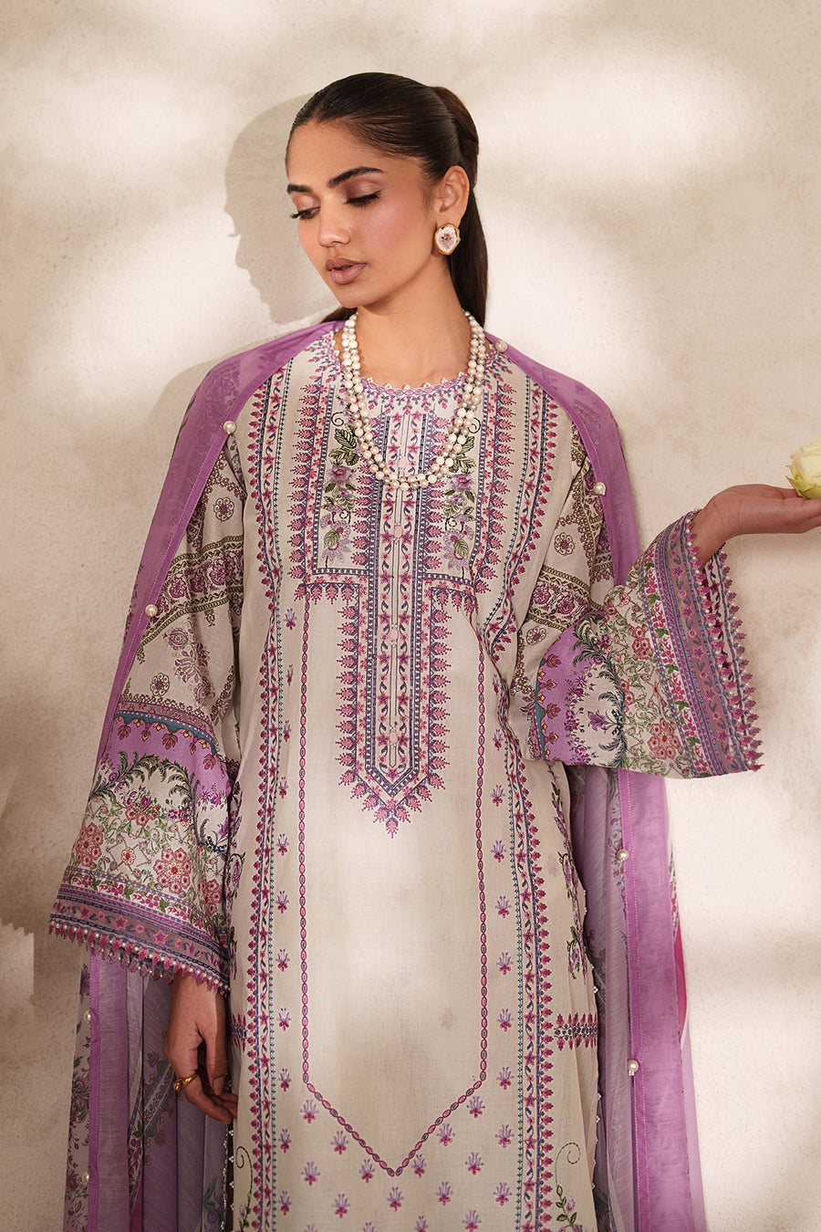 Full frontal view of woman standing in embroidered lawn suit with matching chiffon dupatta draped, showcasing pastel floral patterns and pearl accents.