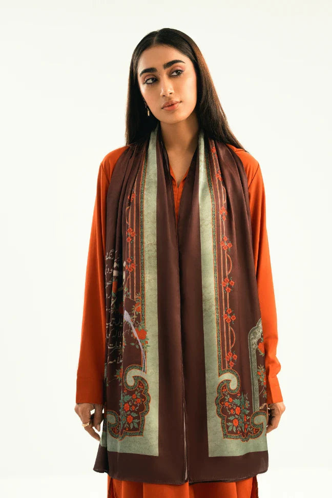 Woman wearing an elegant silk scarf in deep brown and muted green with floral and script print over an orange dress