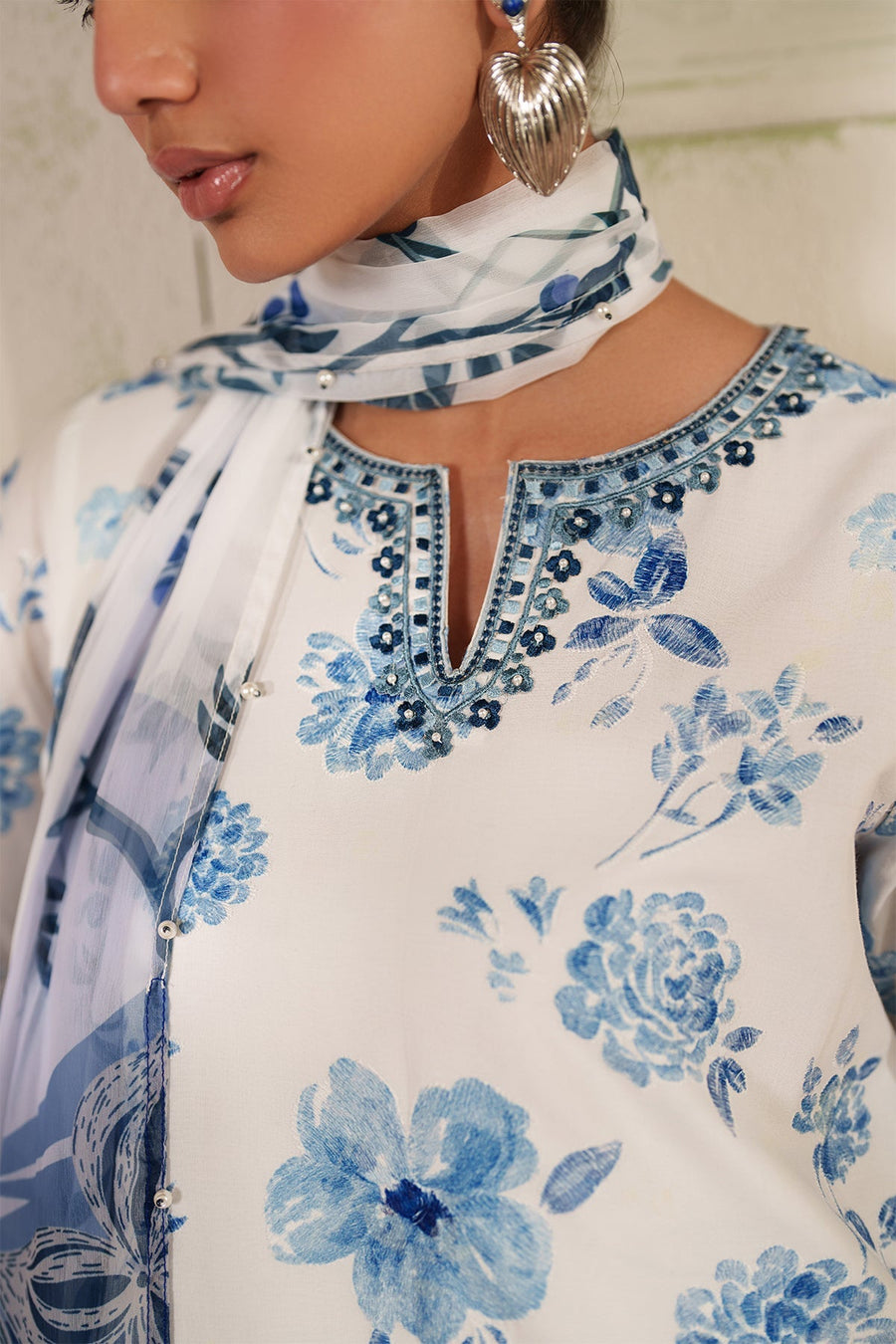 Detailed image of the back neckline embroidery on white fabric with blue floral print and pearl embellishments