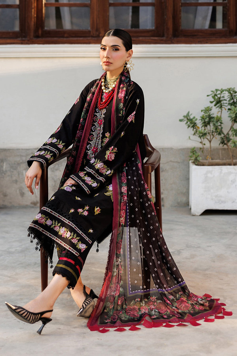 Model seated, elegantly posing in the embroidered floral lawn suit with chiffon dupatta