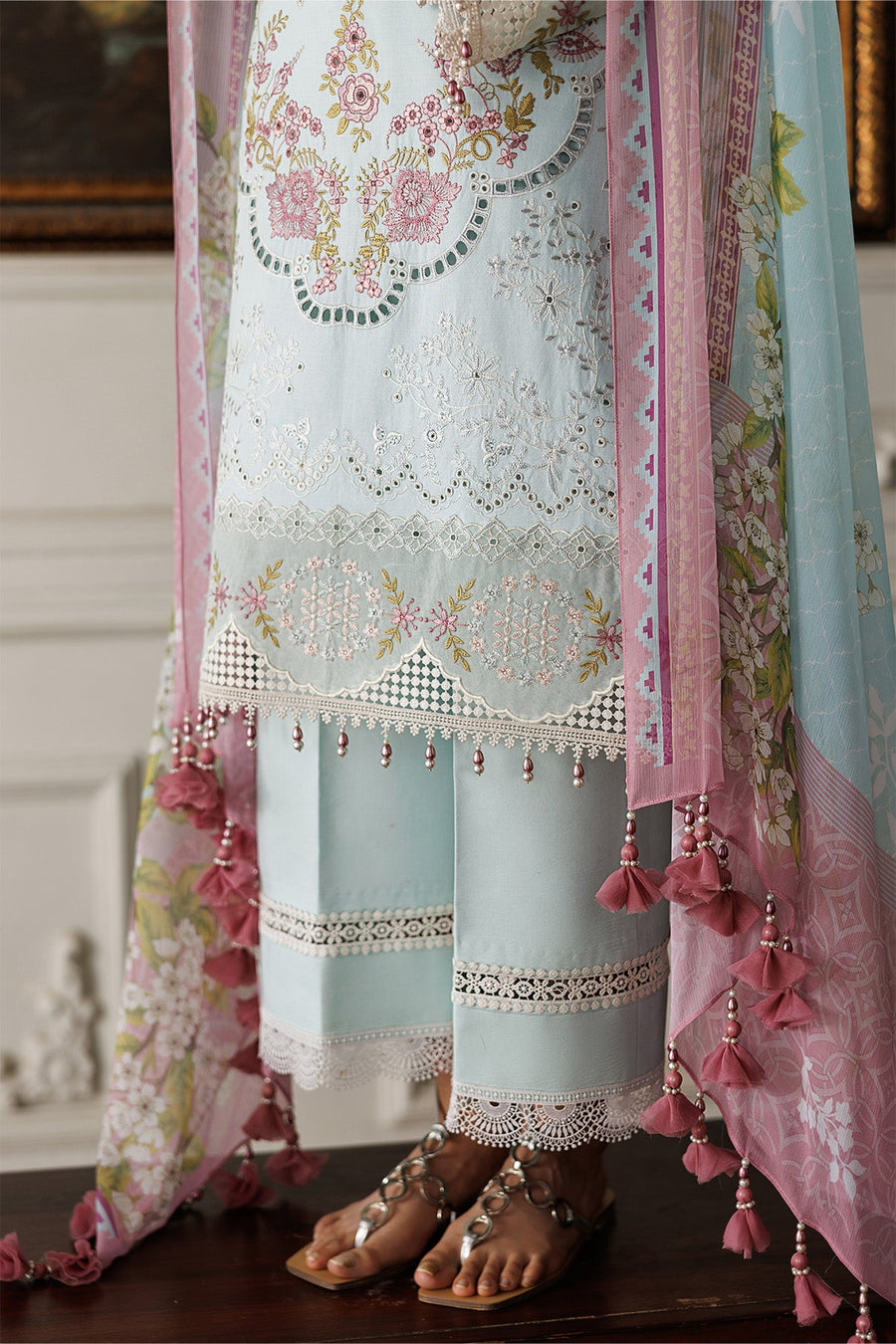 Woman wearing the complete lawn suit set seated, displaying dupatta tassels and shoe detail