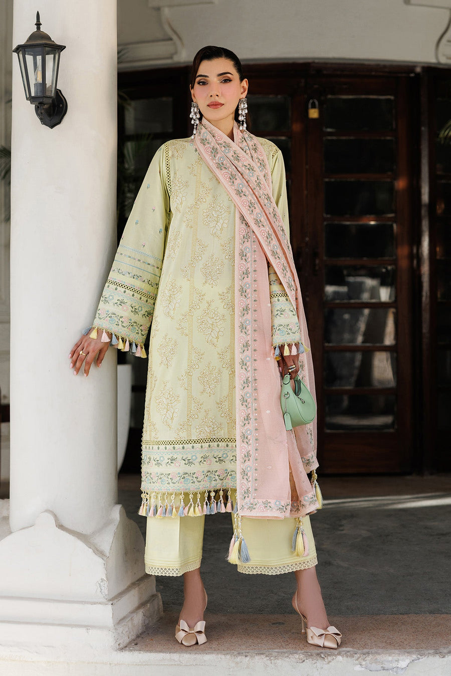 Elegant woman dressed in yellow embroidered lawn shirt with detailed cuffs holding mint green handbag with pink embroidered dupatta