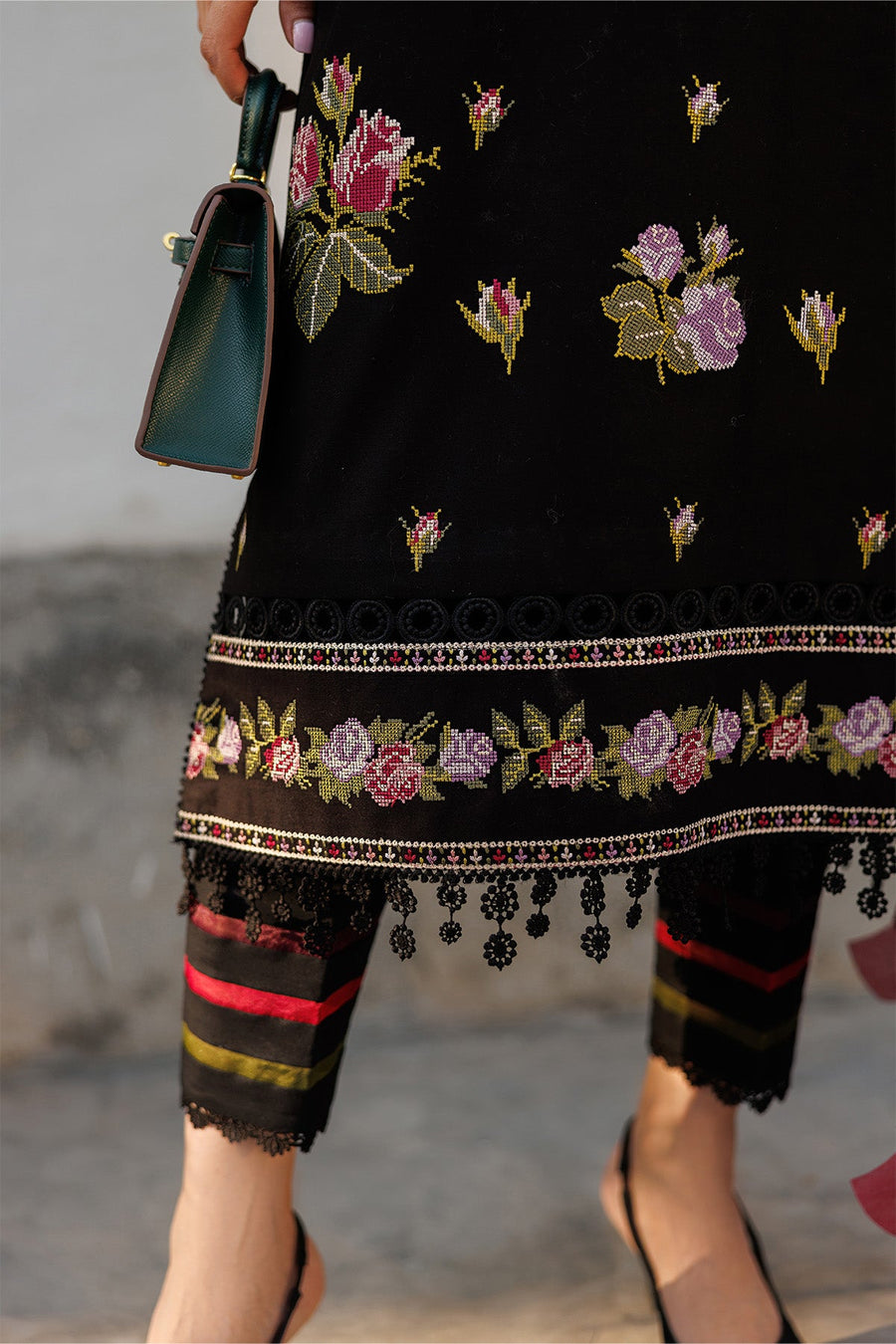Close-up of embroidered floral hem detail on the suit with striped lace-trimmed trousers