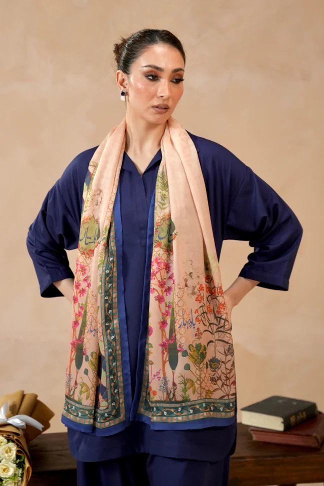 Woman wearing navy blue traditional outfit with a peach crinkle silk scarf featuring colorful floral patterns and Urdu calligraphy
