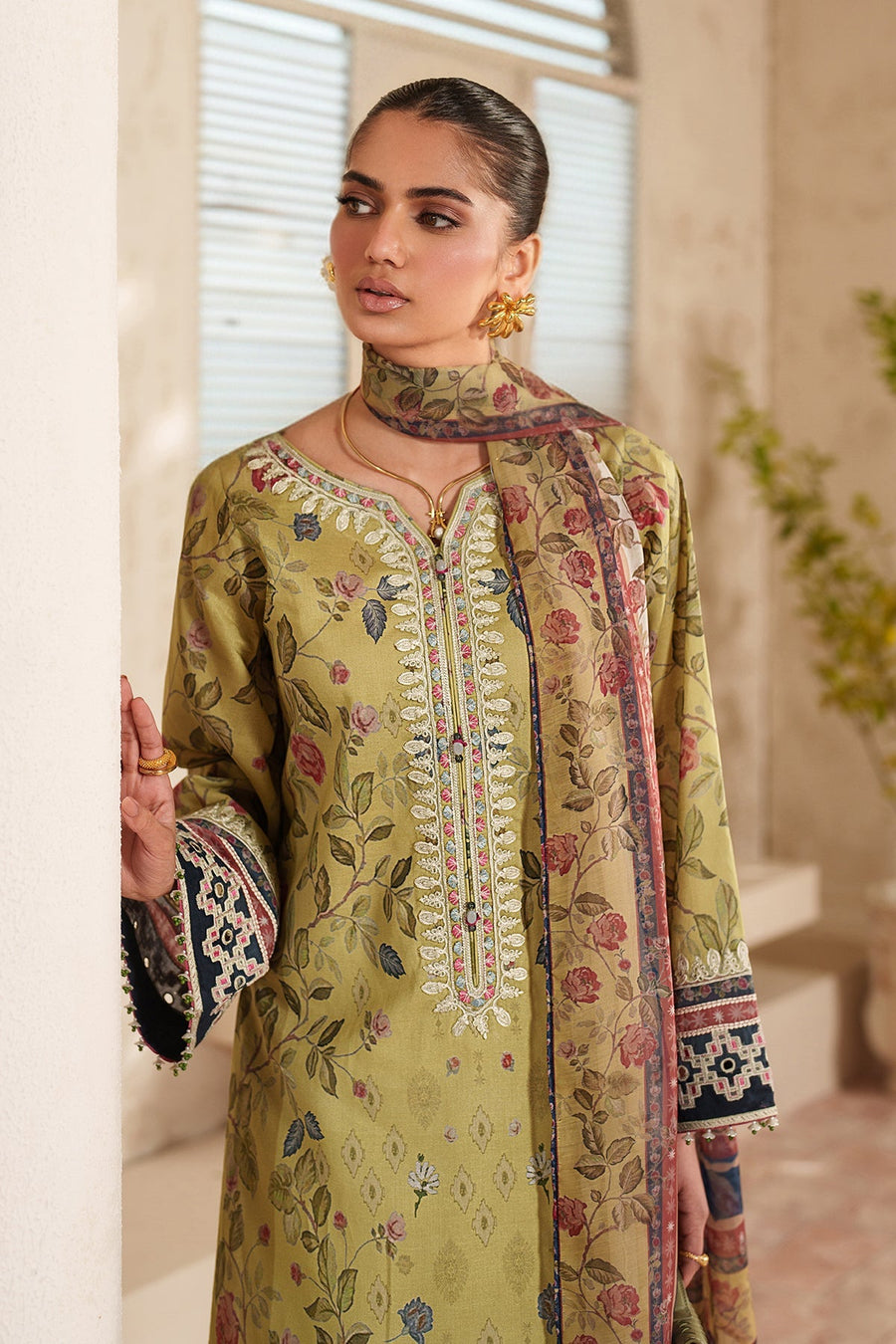 Close-up frontal view of woman showcasing fine detailed embroidery on the neckline and sleeve cuffs of soft green floral lawn shirt