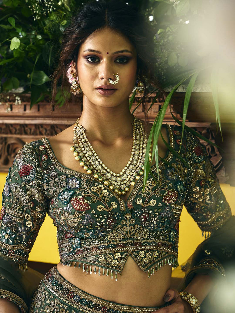 Close-up of model wearing the detailed embroidered blouse of the green lehenga set, featuring beadwork, mirror accents, and a layered pearl necklace with matching earrings and nose ring.
