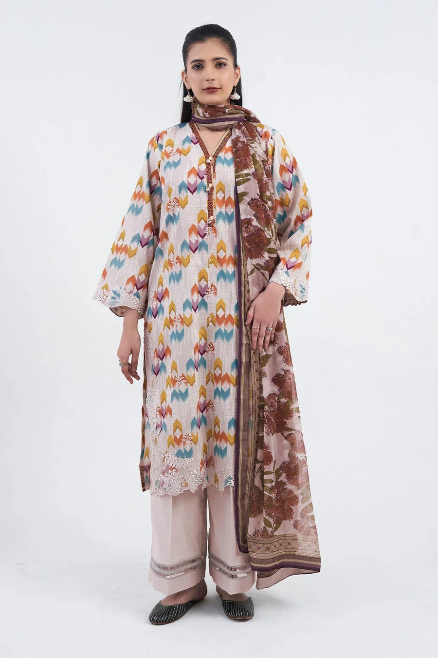 Front view of a woman wearing embroidered three-piece lawn suit with colorful geometric pattern shirt, blush trousers, and floral print chiffon dupatta