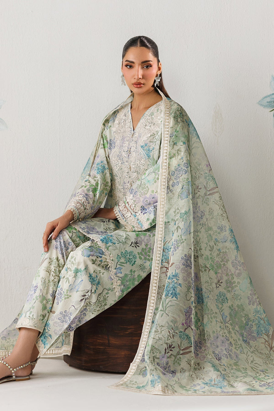 Model seated with sheer embroidered dupatta and floral print suit, showcasing elegant modest styling