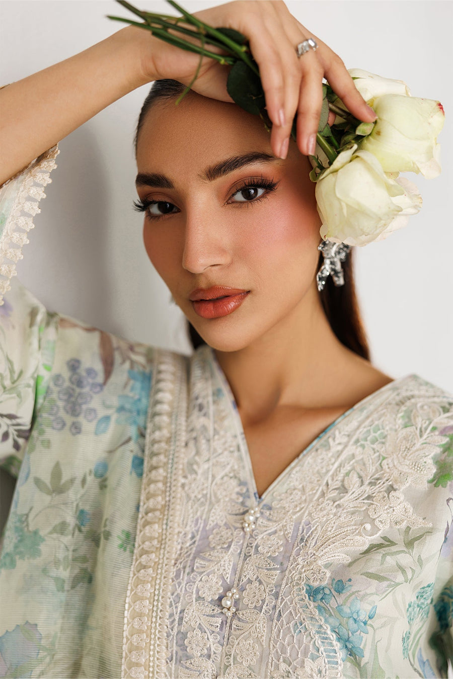 Portrait of woman with floral leaf inspired earrings, showing embroidered lawn fabric and pearl accents