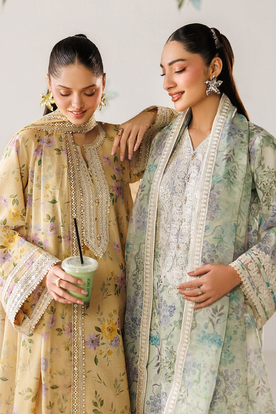 Casual social setting with two women in embroidered lawn suits sipping drinks, highlighting garment versatility