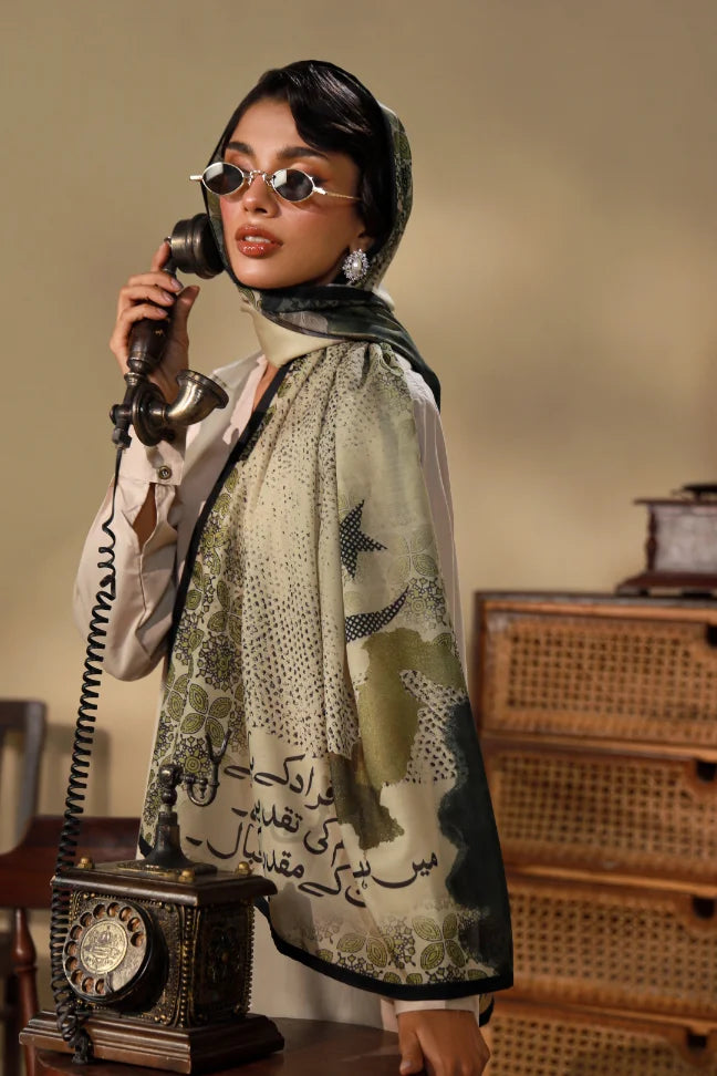 Woman wearing a Swiss lawn scarf with printed Urdu calligraphy, olive and beige color tones, styled with sunglasses and traditional earrings, holding a vintage telephone.