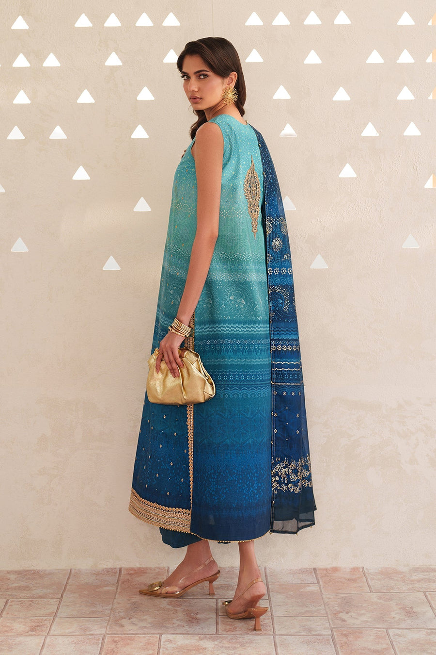 Side view of woman in three-piece embroidered lawn suit with teal and deep blue gradient, showcasing back embroidery and matching printed dupatta