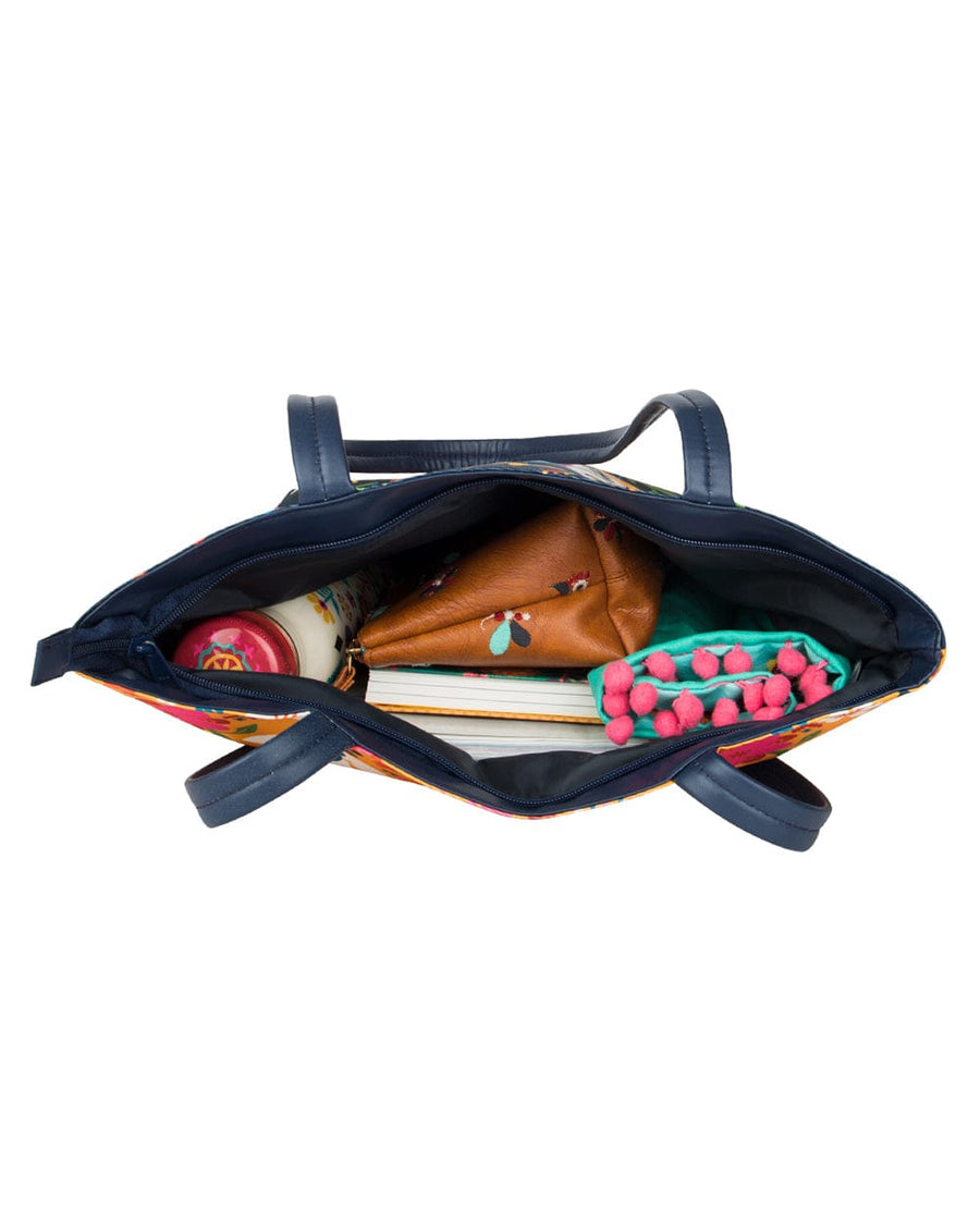 Top-down view of tote bag filled with a water bottle, brown pouch, notebook, and teal scarf
